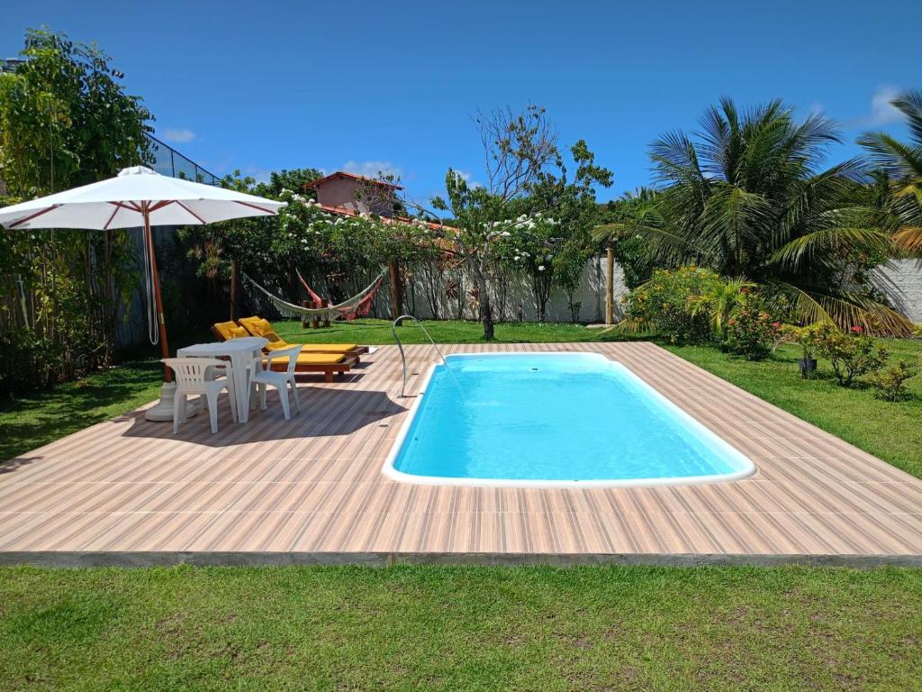 uma piscina com uma mesa e um guarda-sol em Pousada Do Maker em Itacimirim