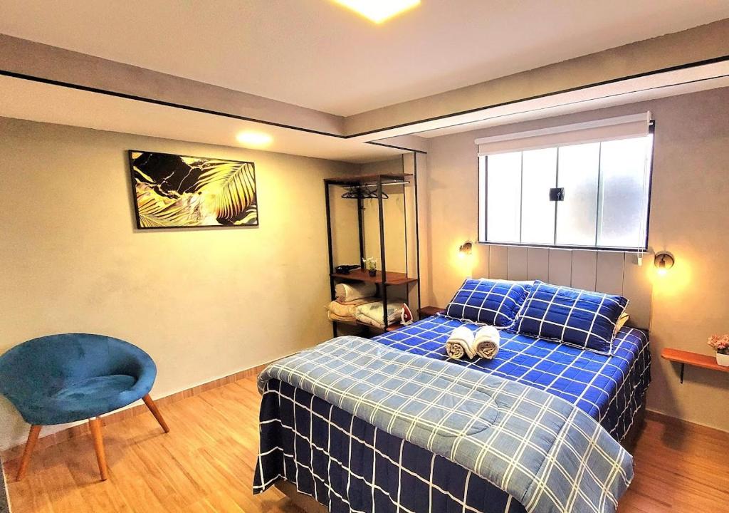 um quarto com uma cama azul e uma cadeira azul em Apartamento 16 Central em Poços de Caldas em Poços de Caldas