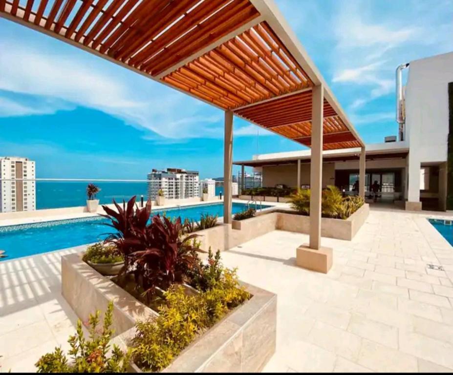 un patio al aire libre con piscina y pérgola de madera en Hermoso ApartaSuite en Playa Salguero!/Rodadero, en Gaira