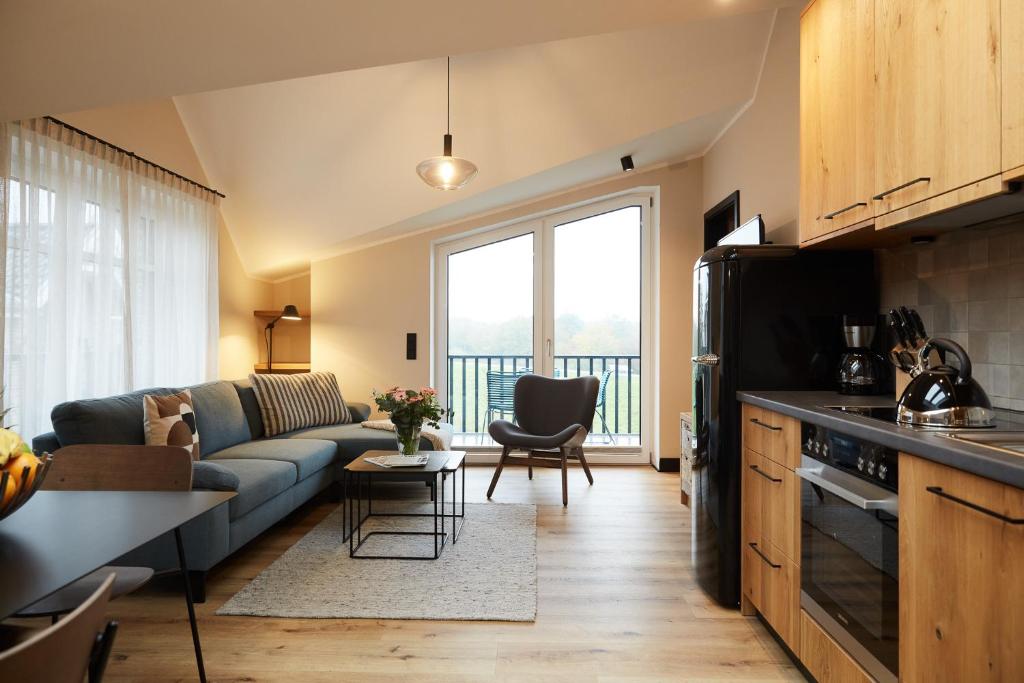 eine Küche und ein Wohnzimmer mit Sofa und Tisch in der Unterkunft Binnendiek Haus 2 Apartment 11 in Büsum