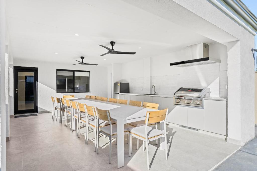 a white kitchen with a white table and chairs at Sea Spray - Aldinga Beach - C21 SouthCoast Holidays in Aldinga Beach