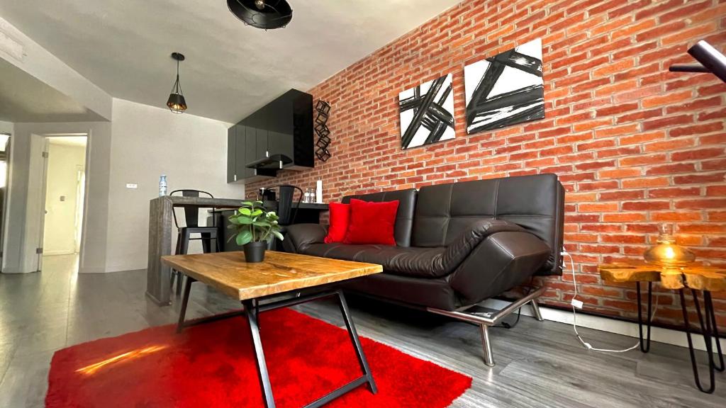 sala de estar con sofá de cuero y pared de ladrillo en •Executive Suite• Quiet, Centrally & Comfortable en Ciudad Juárez