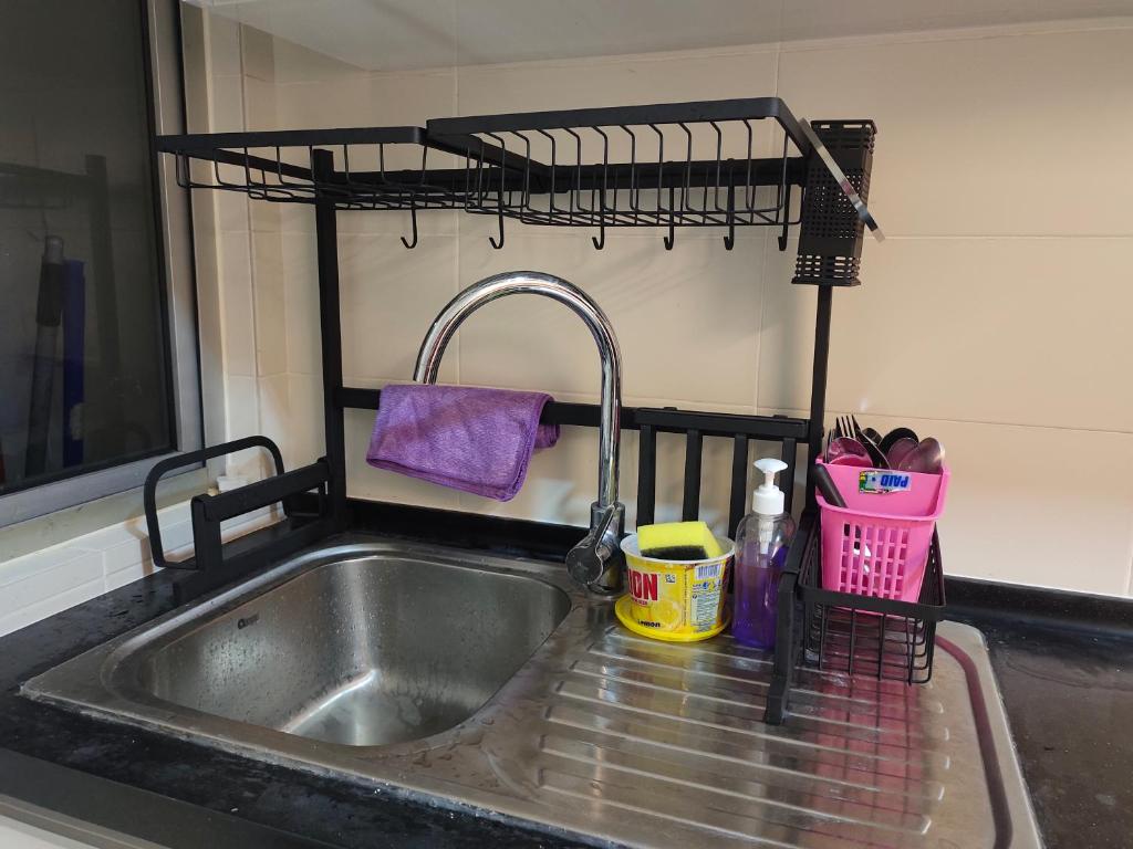 a kitchen sink with a faucet and a drying rack at Homestay Ijan in Cyberjaya