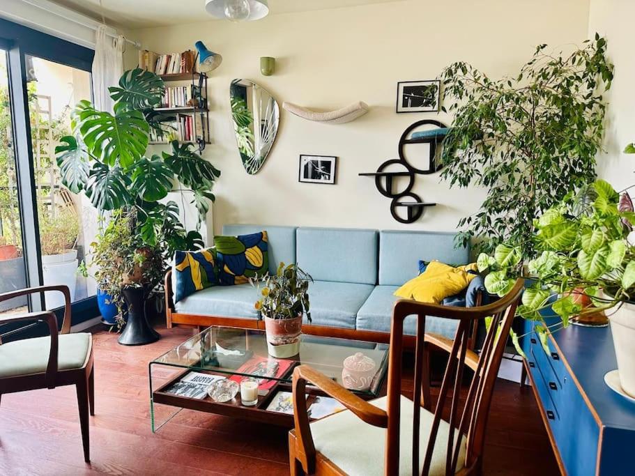 ein Wohnzimmer mit Sofa und vielen Pflanzen in der Unterkunft Confort au cœur des Puces PARIS Appartement modern in Saint-Ouen