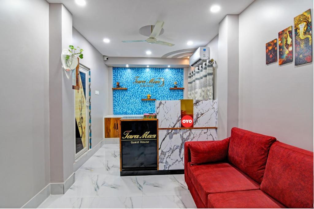 uma sala de estar com um sofá vermelho e uma parede em OYO Tara Maa Guest House em Calcutá