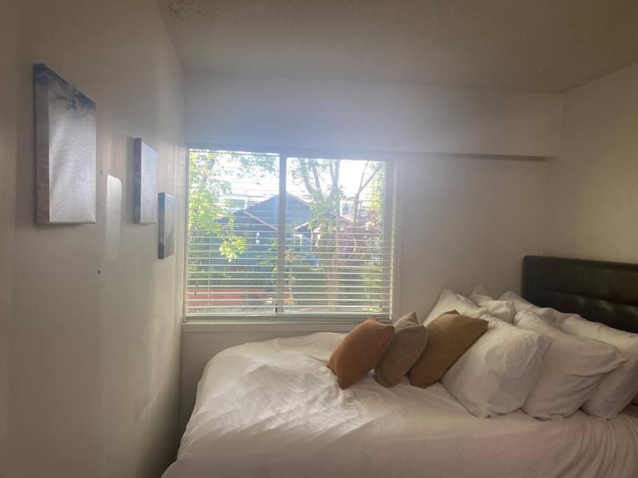 a white bed in a room with a window at 4 bedroom shared home and bath on a quiet tree lined street in Vancouver
