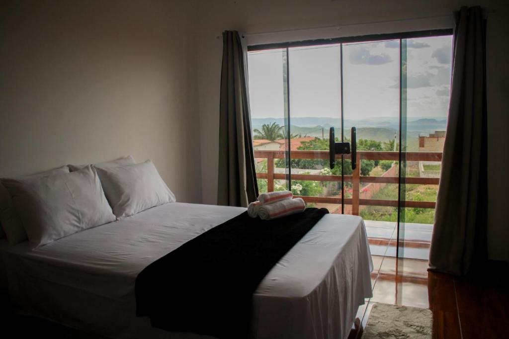 a bedroom with a bed and a large window at Chalé Aconchego da Serra in Serra de São Bento