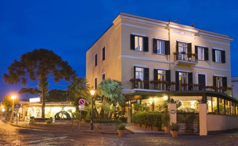 a large white building with lights on a street at Hotel Villa Maria in Ischia