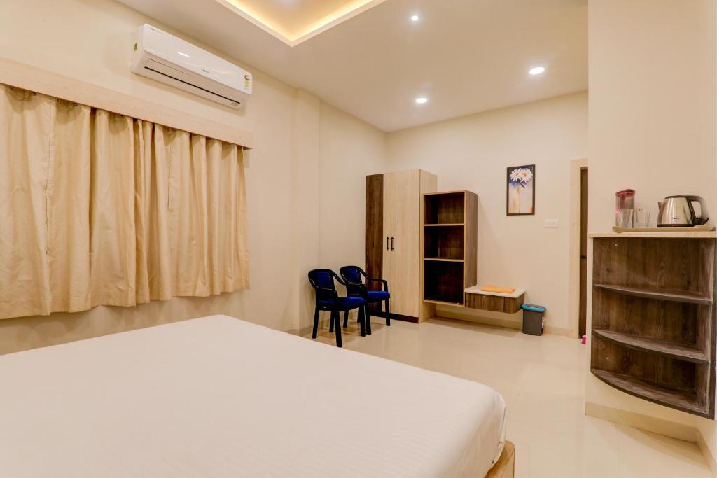 een slaapkamer met een bed en 2 stoelen. bij OYO Hotel Ambika Palace in Patna
