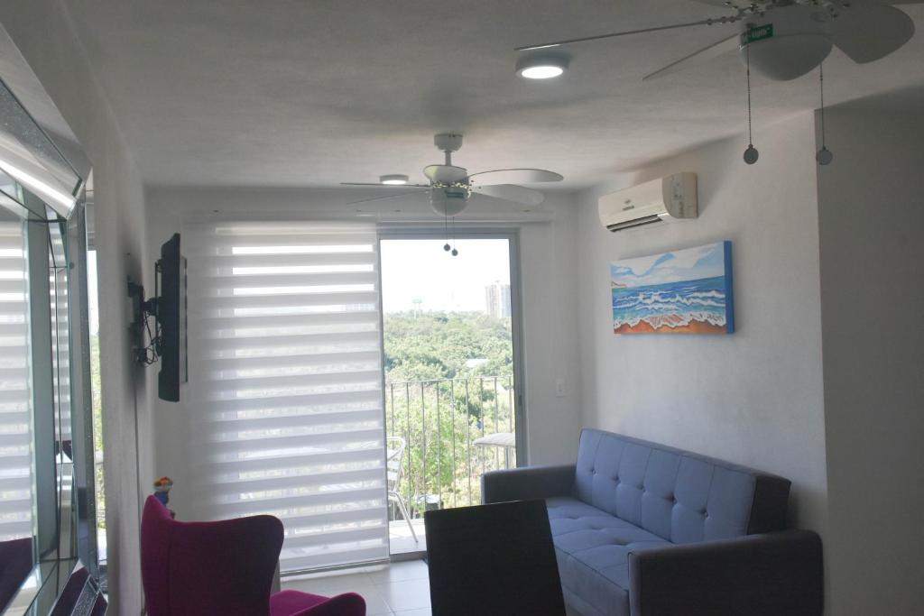 - un salon avec un canapé bleu et une fenêtre dans l'établissement Condominio, Bello Horizonte Plaza, Santa Marta., à Santa Marta