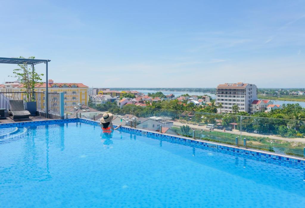 una persona está de pie en una gran piscina en Cozy Savvy Boutique Hotel Hoi An, en Hoi An