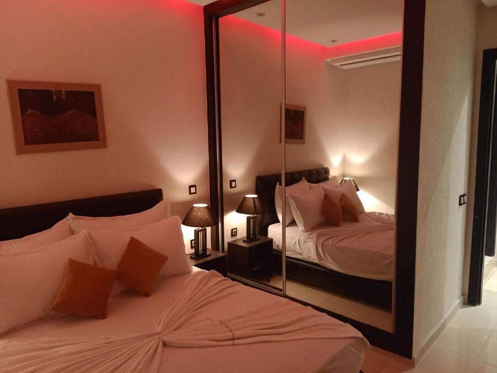 1 dormitorio con 2 camas y espejo en Appartement 55, en Marrakech