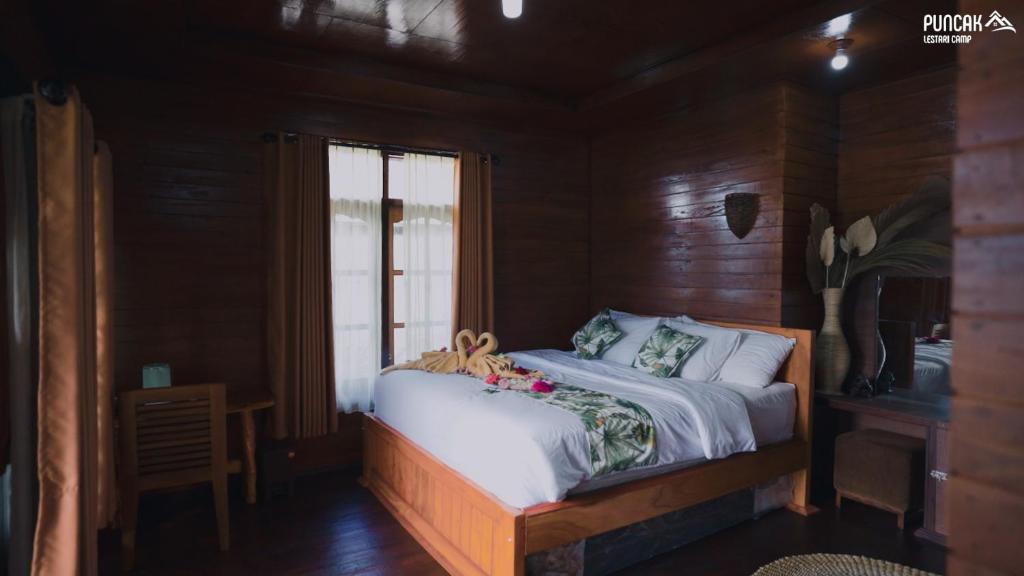 ブドゥグルにあるPuncak Lestari Villa Bedugul by BIJAKの窓付きの木造の部屋のベッド1台