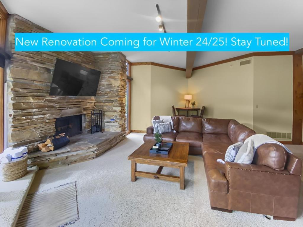 sala de estar con sofá de cuero y chimenea en 24B Powder Run condo, en Park City