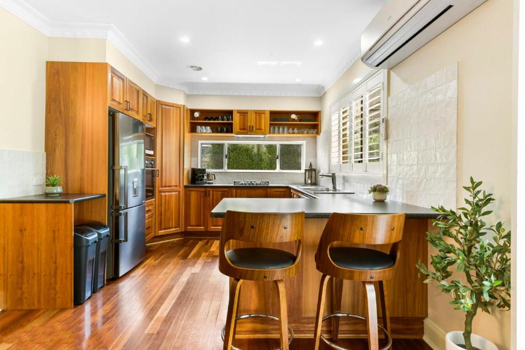 a kitchen with wooden cabinets and a island with bar stools at Roselawn Manor - 5 Bedroom Entertainer in Orange