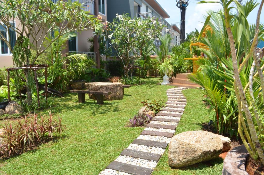 a garden with a stone path in front of a building at David Residence in Nai Yang Beach