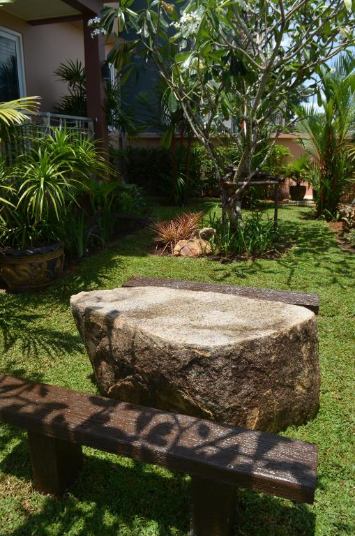 a stone bench in a garden with a tree at David Residence in Nai Yang Beach