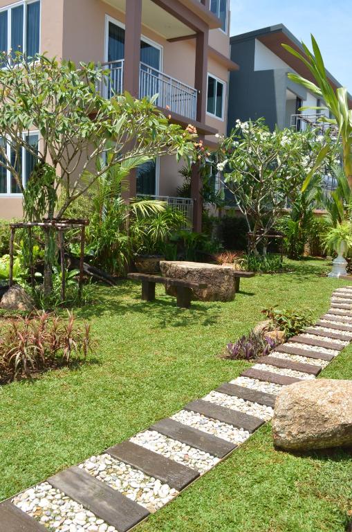 a garden with a stone path in front of a building at David Residence in Nai Yang Beach