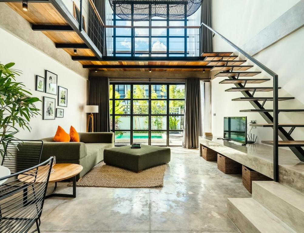 sala de estar de planta abierta con escalera y sofá en Berawa Loft 10 by Betterplace, en Canggu