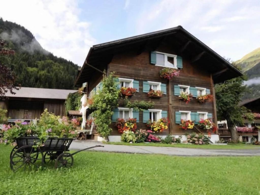 a wooden house with flowers in front of it at Comfortable house with garden in Voralberg in Sankt Gallenkirch