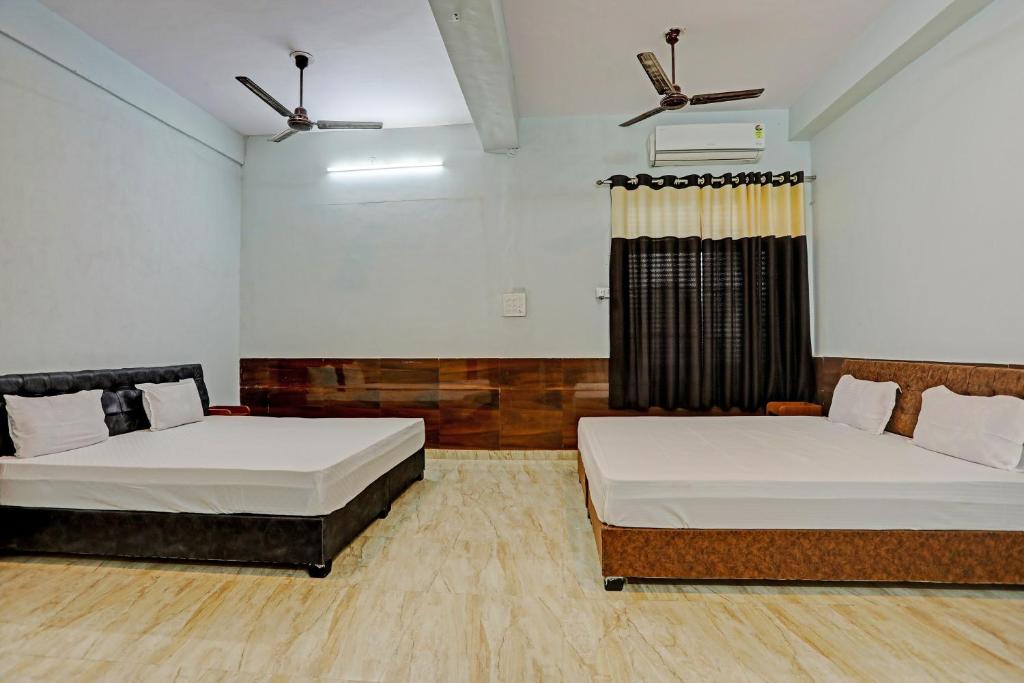a bedroom with two beds and a window at Nidhivan Guest House in Kishangarh