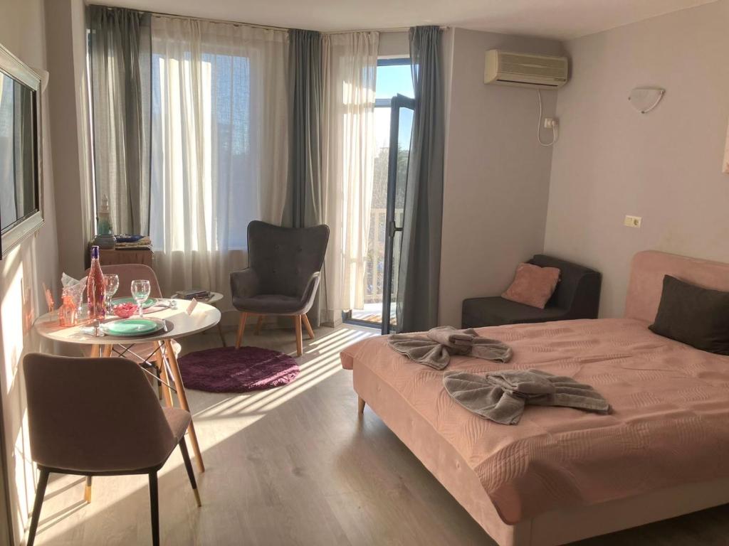 a bedroom with a bed and a table and chairs at Joy Apartment Sunny Beach in Sunny Beach