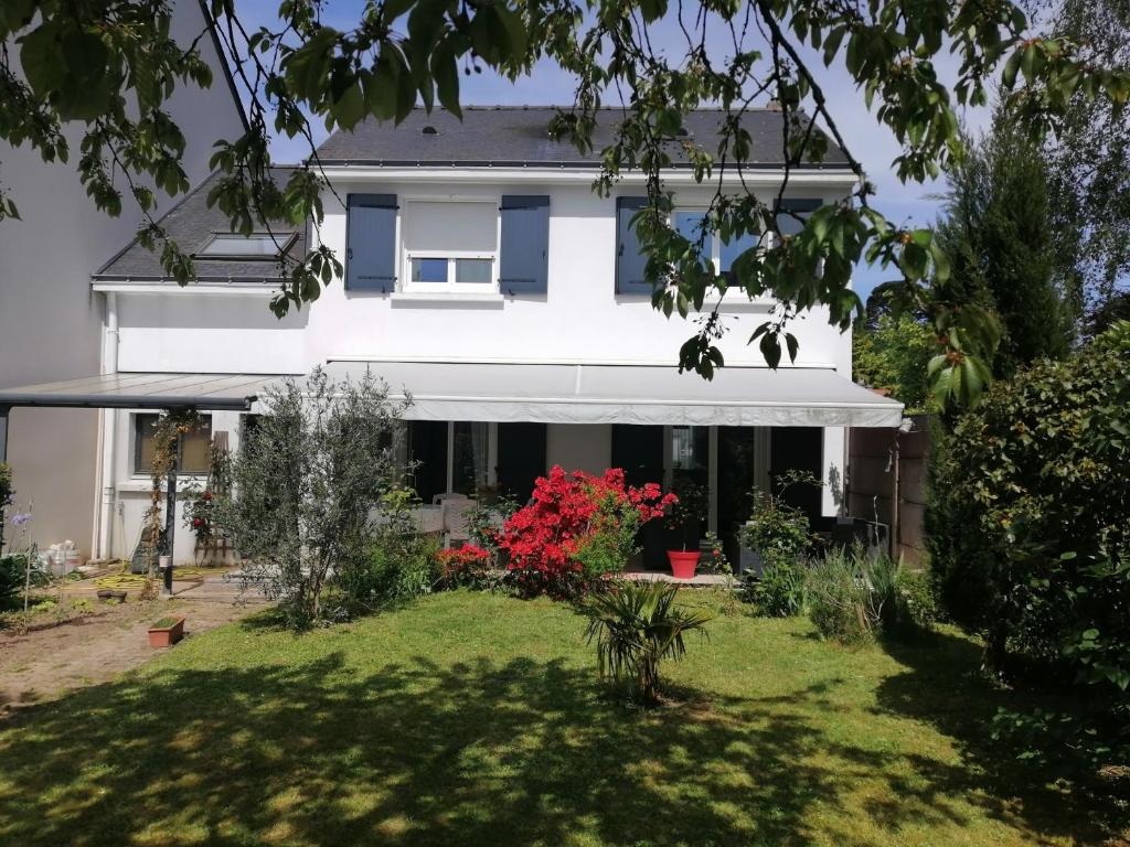 una casa blanca con un patio con flores rojas en Chantilly, en Orvault