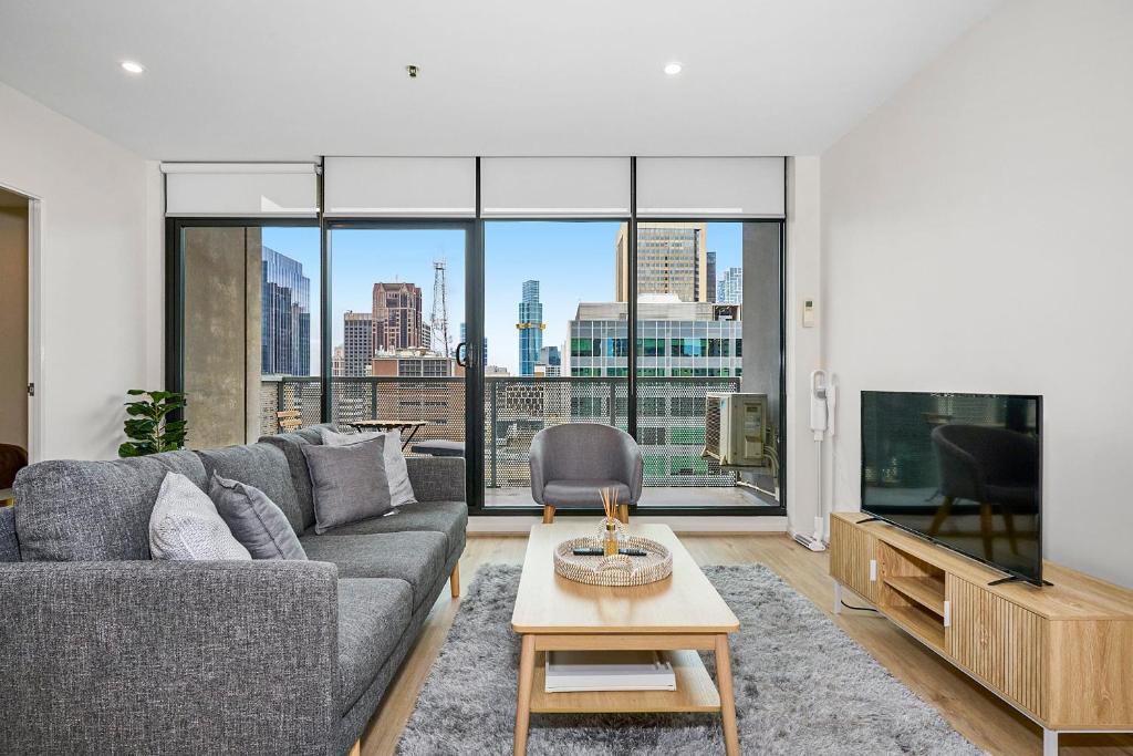 a living room with a couch and a large window at Luxe Lonsdale - Your City Retreat in Melbourne in Melbourne