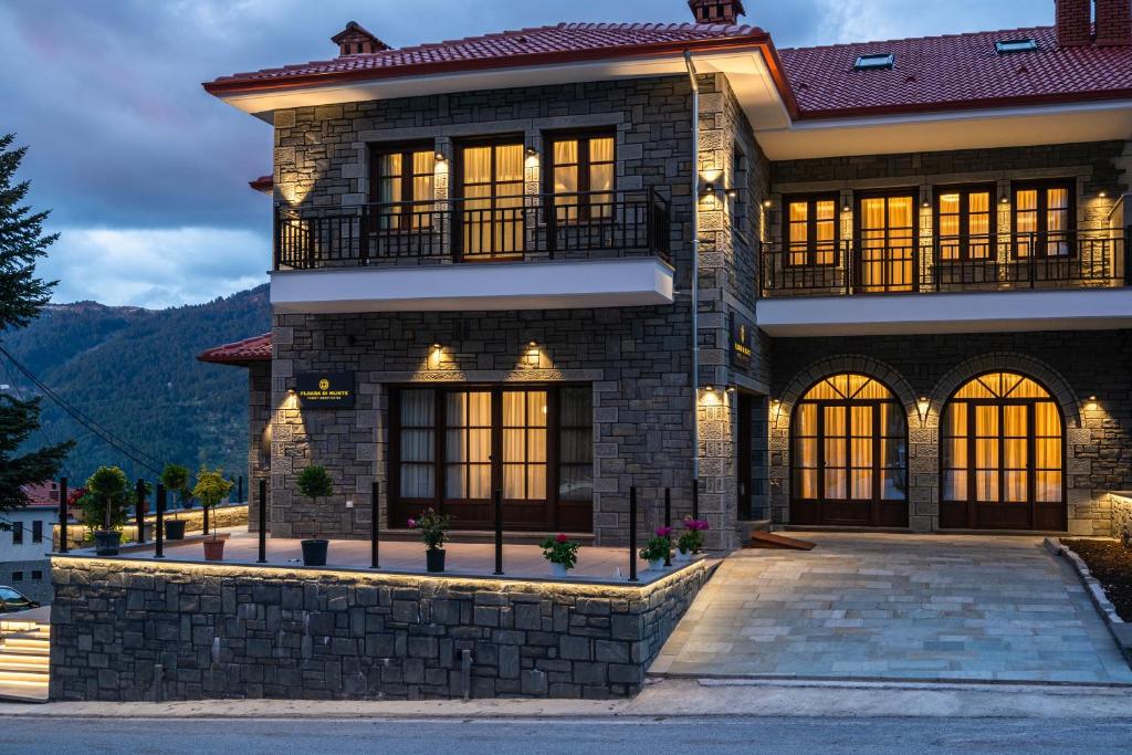 Une maison avec des montagnes en arrière-plan dans l'établissement FLOARA DI MUNTE Forest Luxury Suites, à Metsovo