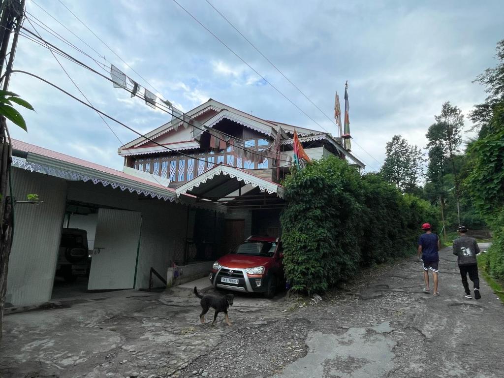 Mountaintop Guest House في Bhurtuk: شخصين وكلب يقف أمام المنزل