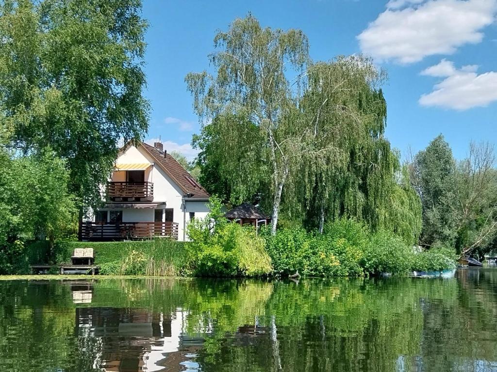 a house next to a lake with trees and water at Ferienwohnung 'im Havelhaus' in Ketzin
