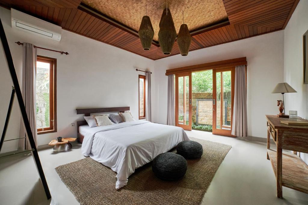een slaapkamer met een bed en een tafel en ramen bij 26# 2 bed Parq Ubud in Ubud