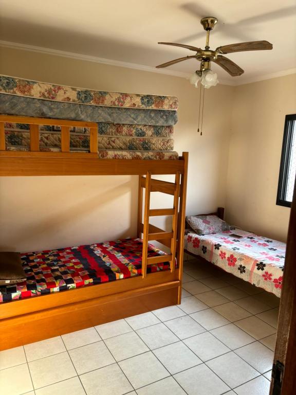 Un dormitorio con dos literas y un ventilador de techo. en Apartamento beira-mar em Mongaguá, en Mongaguá
