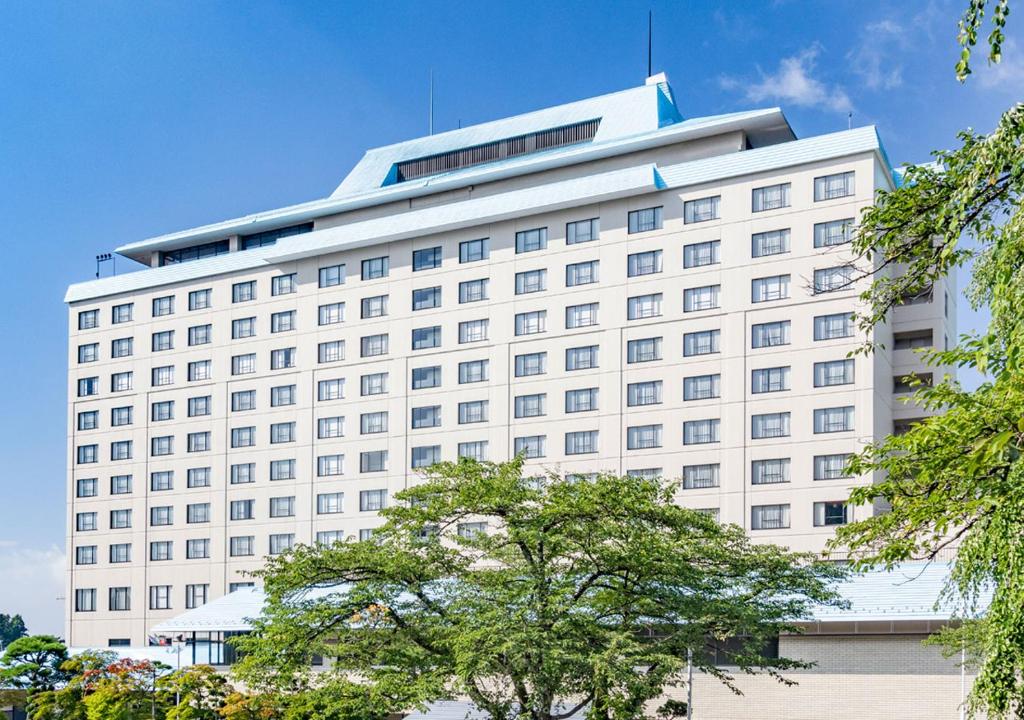 ein großes weißes Gebäude mit vielen Fenstern in der Unterkunft Hotel Senshukaku in Hanamaki