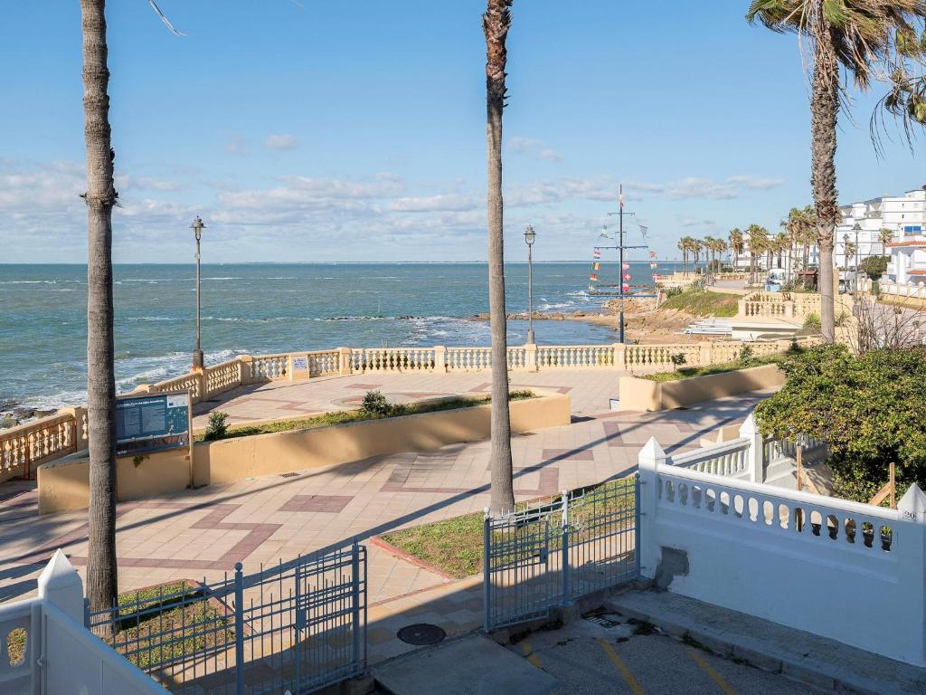 vista sulla spiaggia e sull'oceano con palme di Traditional holiday home with terrace a Chipiona