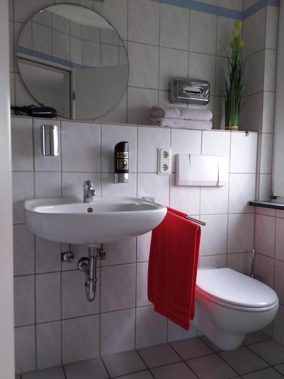 ein Badezimmer mit einem Waschbecken, einem WC und einem Spiegel in der Unterkunft Pension Breidbach in Ensch