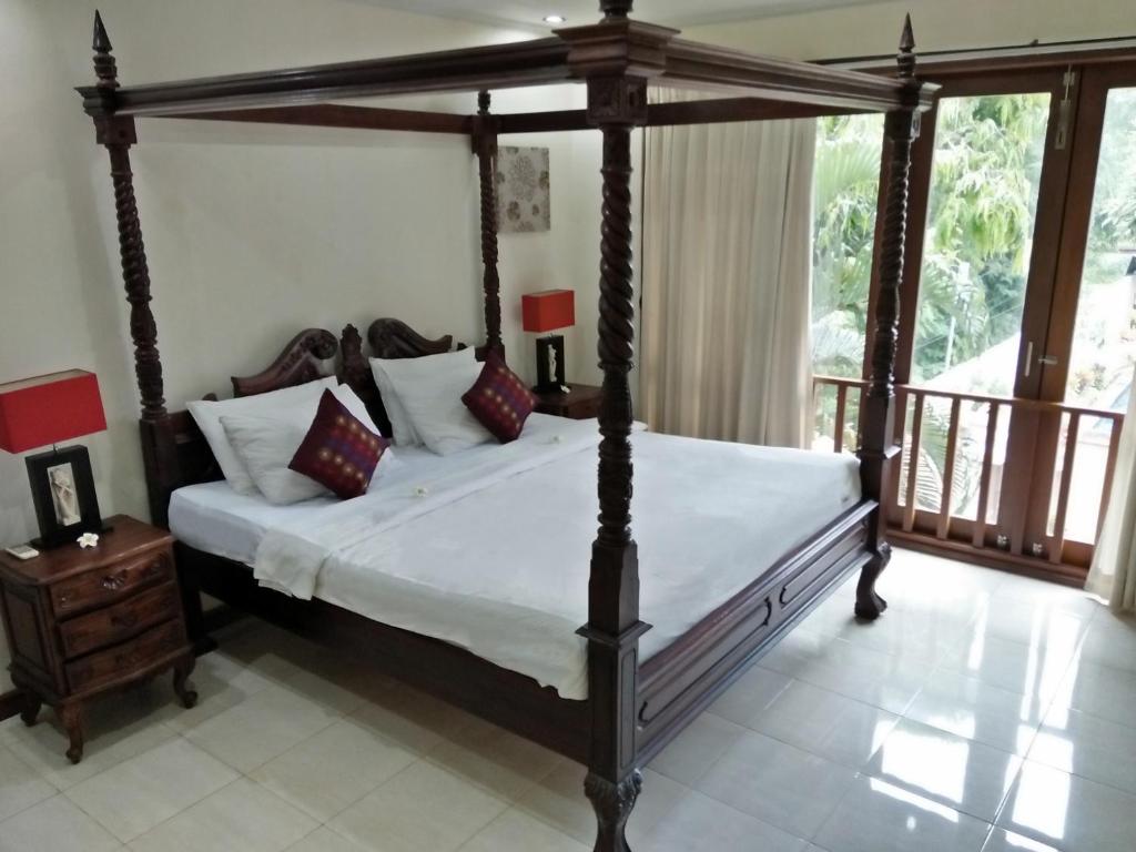 a bedroom with a canopy bed and a balcony at Sekuta Condo Suites in Sanur