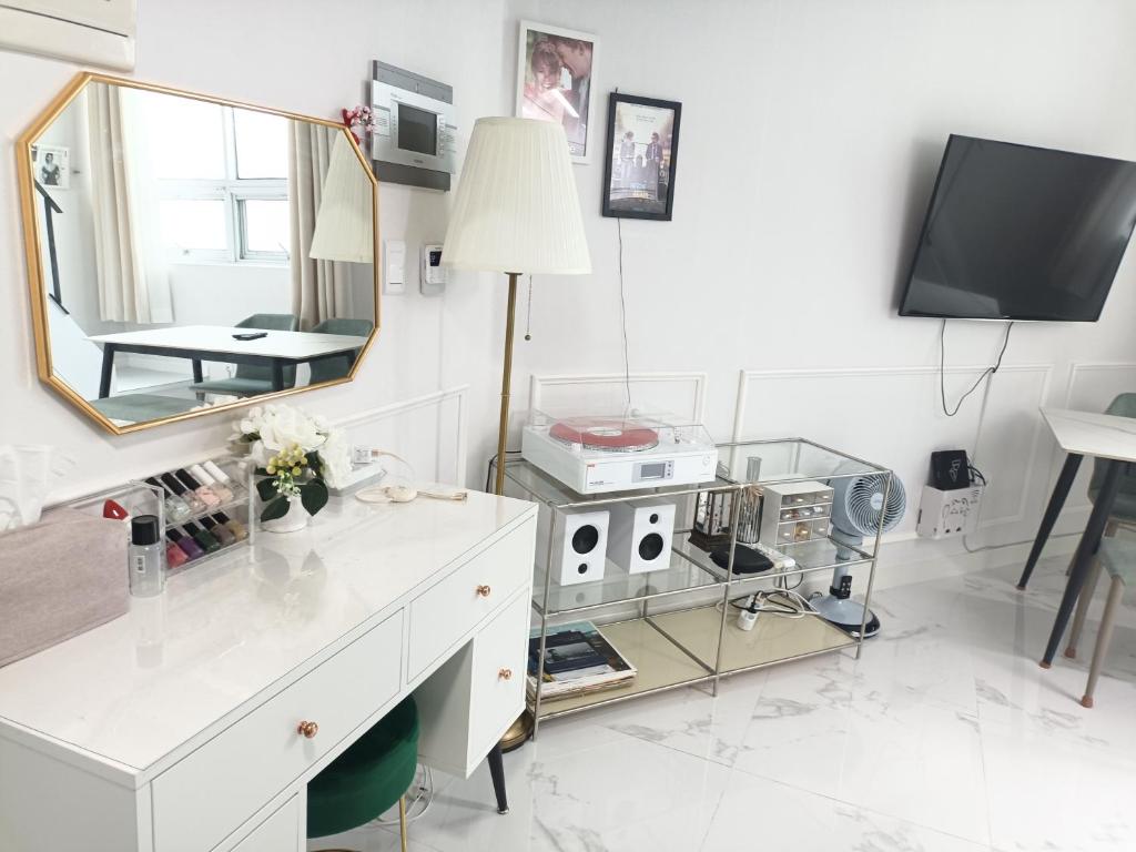 een witte kamer met een spiegel en een kaptafel bij Blooming Guest House in Daegu