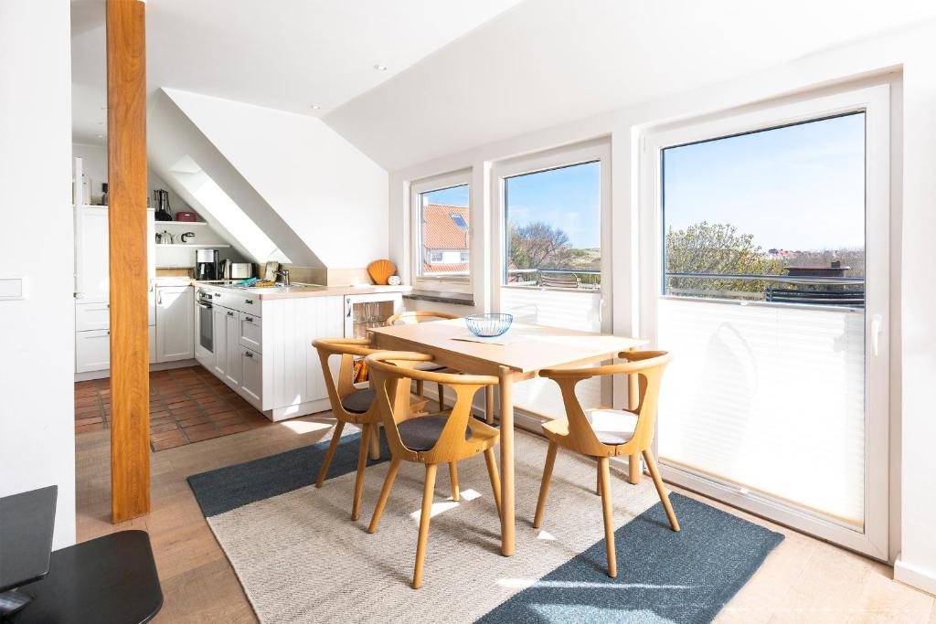 a kitchen with a table and some chairs and windows at Fofftein in Juist