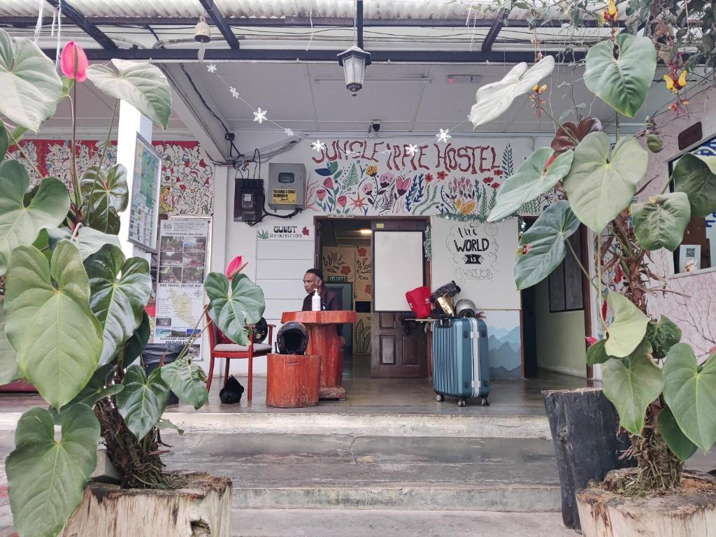 a man sitting at a desk in front of a building at Jungle Ippie Hostel in Tanah Rata