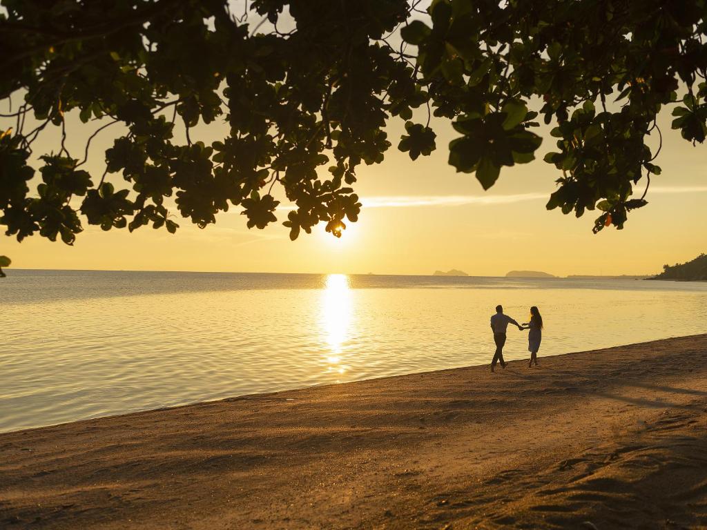 a couple walking on the beach at sunset at Explorar Koh Phangan - Adults Only Resort and Spa in Haad Rin