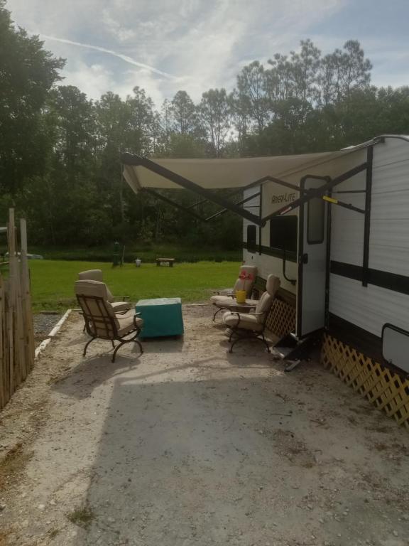 an rv with a tent and chairs in a yard at Clam haven in Crystal River