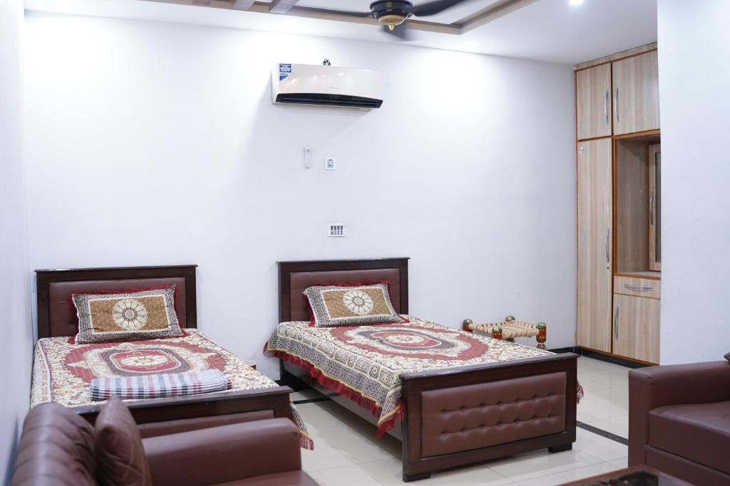 a bedroom with two beds and a couch at Mohal's House in Lahore
