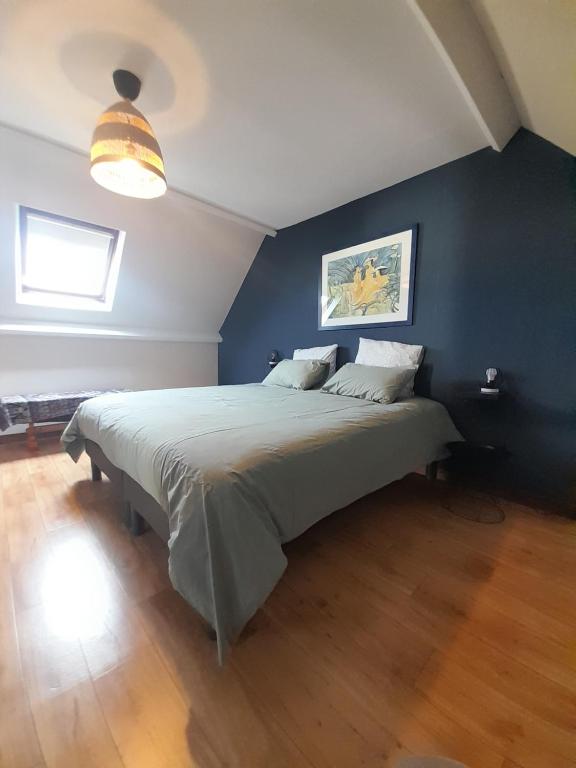une chambre avec un grand lit avec un mur bleu dans l'établissement Le bon plan entre Caen et la mer ** Draps et ménage inclus !**, à Giberville