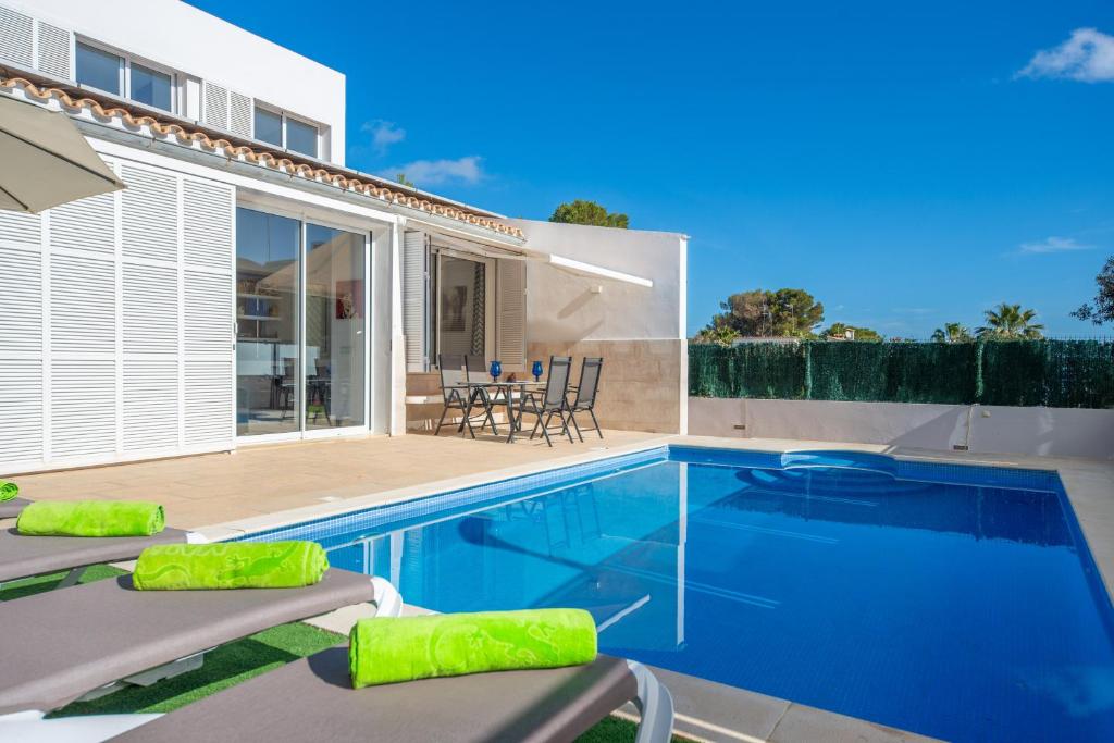 a swimming pool with lounge chairs next to a house at Domus Genti in Son Serra de Marina