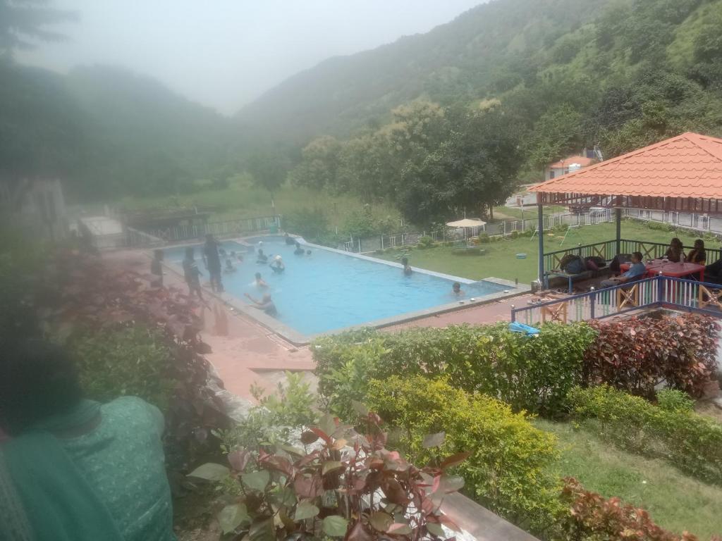 a swimming pool in the mountains with people in it at Maruti Paradise Resort in Udaipur