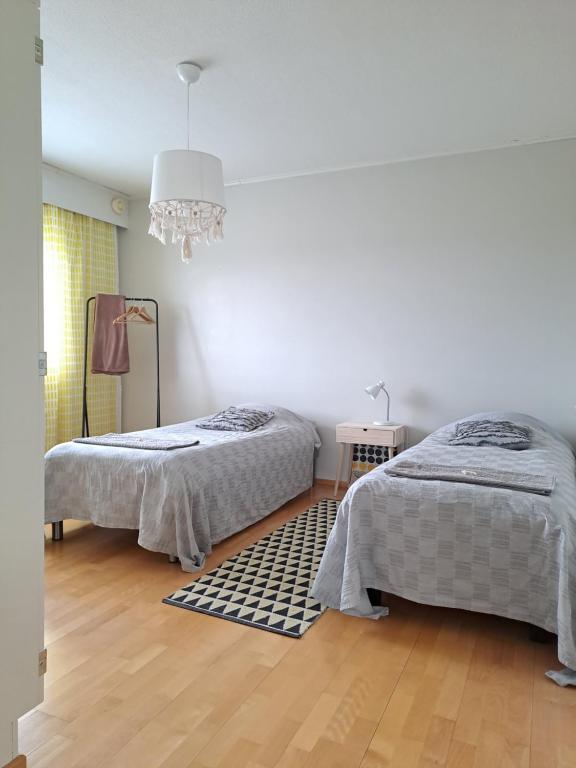 a bedroom with two beds and a chandelier at Tilava kolmio keskustassa in Ylivieska