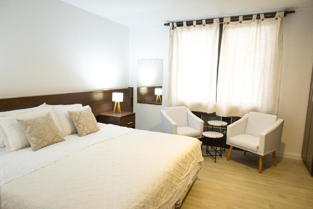 sypialnia z dużym łóżkiem i 2 krzesłami w obiekcie Edifício Flat Hotel Congonhas w São Paulo