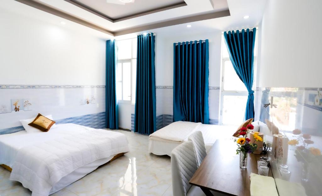 a bedroom with blue curtains and a bed and a desk at Hotel Trâm Anh in Nhơn Trạch