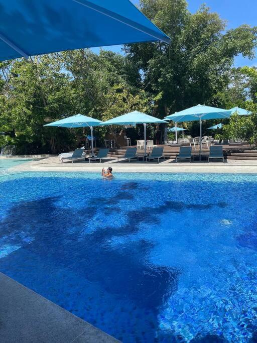 a person swimming in a pool with blue umbrellas at Ma Roberta - Tambuli Resort with fast Wifi 16 Floor Studio Type in Lapu Lapu City